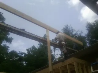 Carpenter setting a ridge beam over a new addition frame — Ice Dam Removal by Roofing Brothers in Douglasville