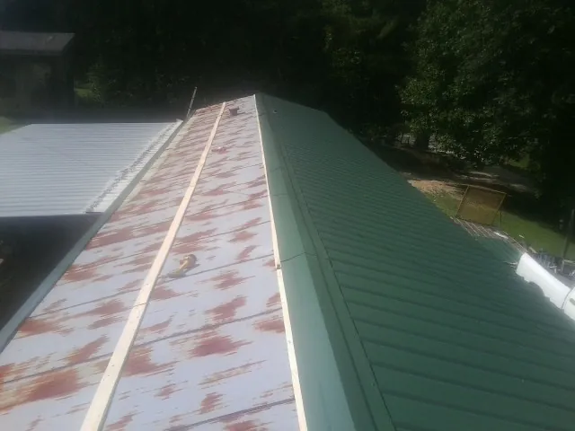 Old rusted panels beside newly installed green metal roofing — Wind Damage Roof Repair by Roofing Brothers in Douglasville