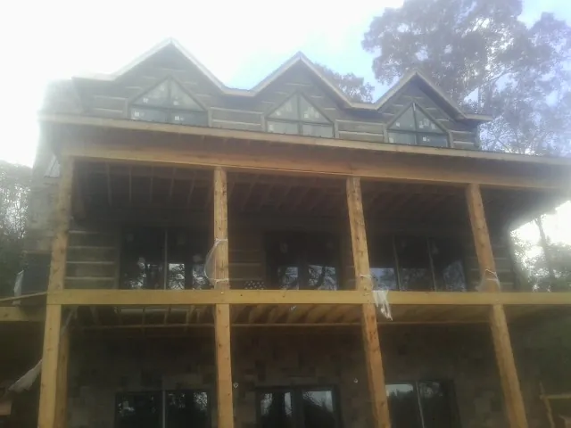 Dormers and porch framing on a large log home under construction — Roof Coating work by our crew in Douglasville