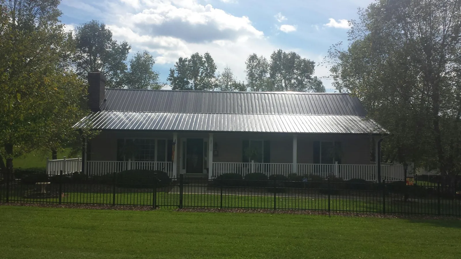 Gray metal roof on a brick ranch with a full width front porch — Gutter Guard Installation work by our crew in Douglasville