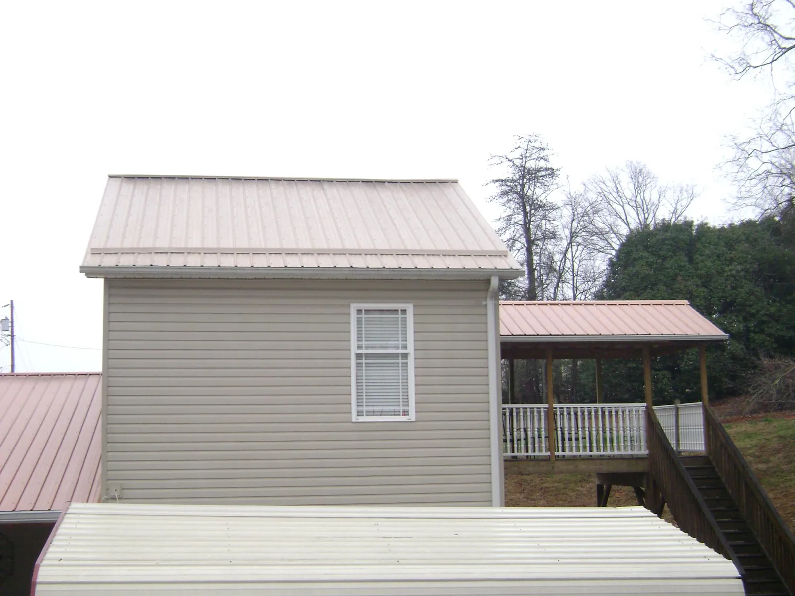 Tan metal roofs on a two story addition and attached porch, from a Roof Replacement job in Douglasville