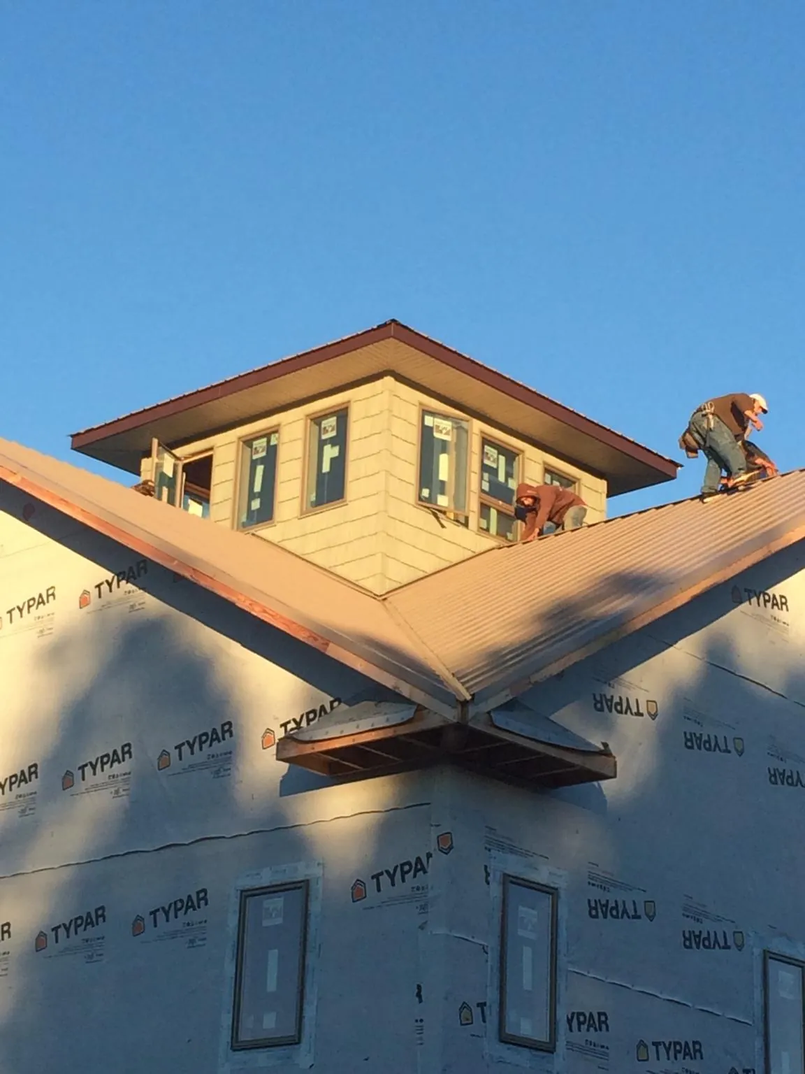 Roofers working around a rooftop cupola on a new metal roof at sunset — Roof Waterproofing in Douglasville by Roofing Brothers